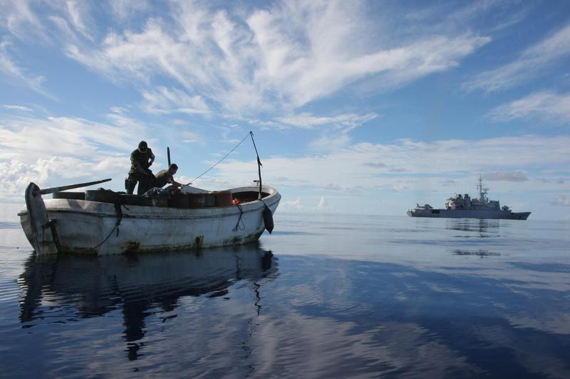 Two French soldiers (R) inspect the boat that held three pirates who where captured and taken to the French warship 'Nivose', (Back) in the North Seychelles area of Indian Ocean. April 30, 2009