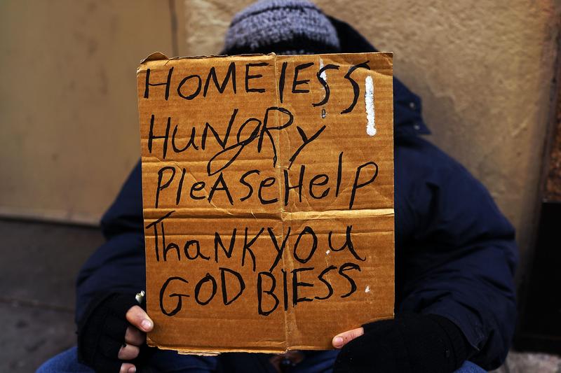 A person in economic difficulty holds a homemade sign asking for money along a Manhattan street on December 4, 2013 in New York City.