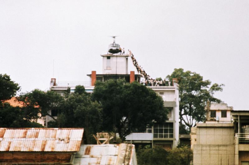 A CIA employee helps Vietnamese evacuees onto an Air America helicopter from the top of 22 Gia Long Street, a half mile from the U.S. Embassy. April 29, 1975