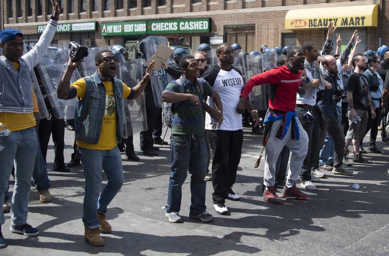 Demonstrators standing in front of a police line call for peace after a bottle was thrown at them on W. North Avenue in Baltimore, Maryland, April 28, 2015.