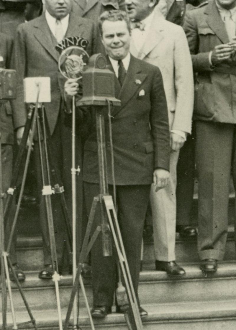 WNYC Announcer Tommy Cowan on the steps of City Hall with the WNYC mic in 1932.
