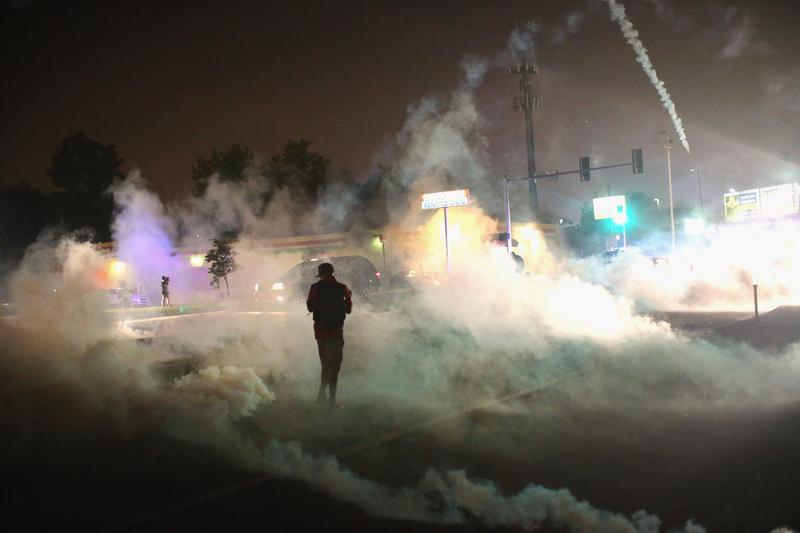 A person runs through a clowd of tear gas that police launched at demonstrators protesting the killing of teenager Michael Brown on August 17, 2014 in Ferguson, Missouri.