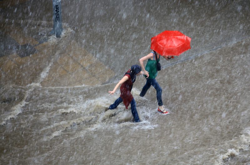People try to cross a flooded road in the center of city on June 15, 2011 in Macedonia, Thessaloniki, Greece.
