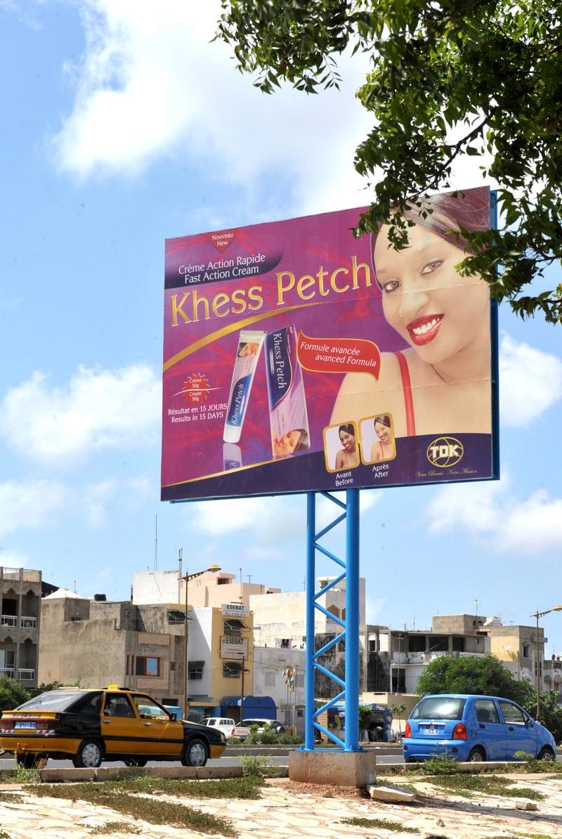 Cars pass by a billboard advertising a skin lightening product called 'Khess Petch' on October 10, 2012 in Dakar.