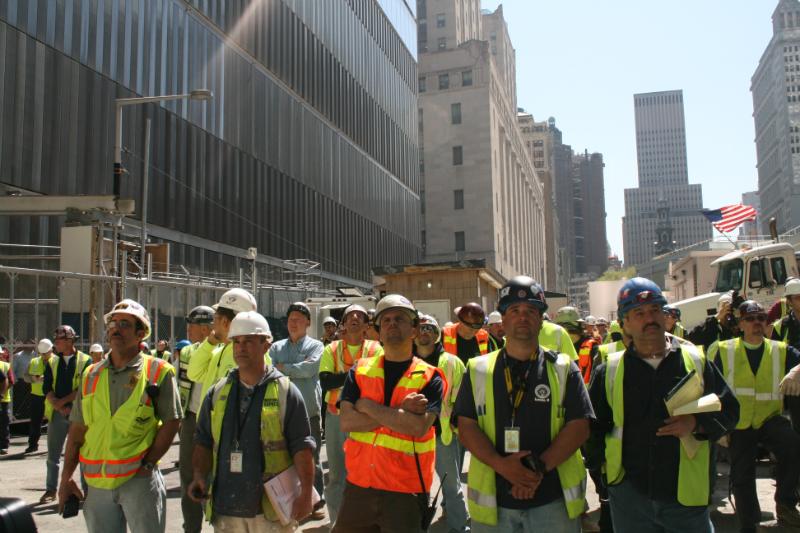 Construction workers watch as a 408-foot spire is hoisted onto One World Trade Center.