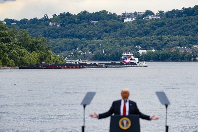 A coal barge is positioned as a backdrop behind President Donald Trump as he speaks about infrastructure during a rally at the Rivertowne Marina, Wednesday, June 7, 2017, in Cincinnati.