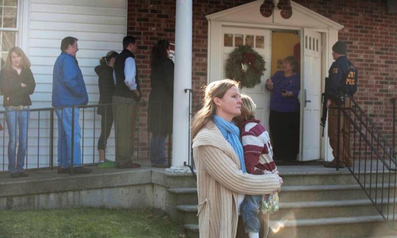 A woman holds a child as people line up to enter the Newtown Methodist Church near the the scene of an elementary school shooting on December 14, 2012 in Newtown, Connecticut.