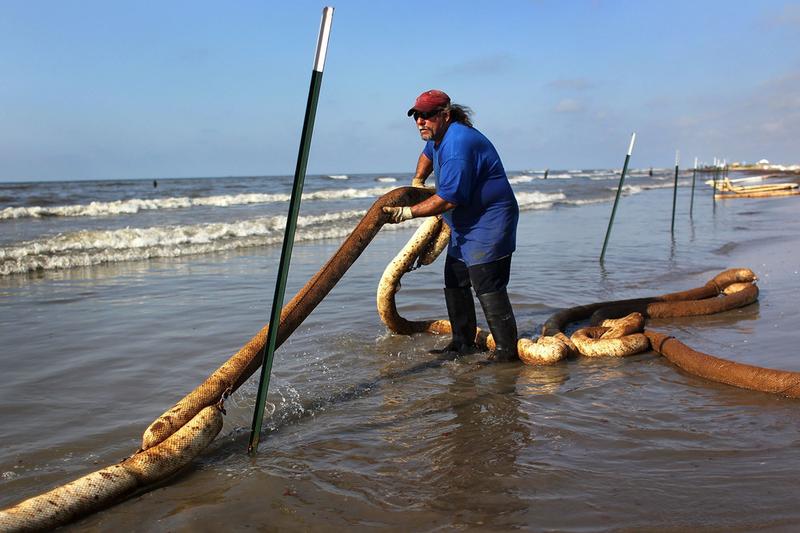 BP cleanup worker Perry LeBoef stretches an oil-soaked boom along a beach on May 23, 2010 on Elmer's Island, Louisiana. Officials now say that it may be impossible to clean the oil-affected wetlands.