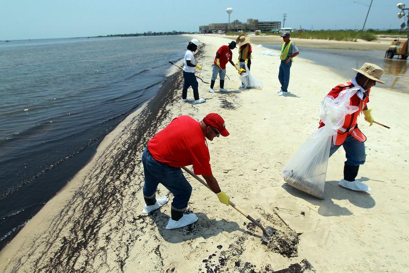 Workers clean up oily globs that washed ashore from the Deepwater Horizon oil spill in the Gulf of Mexico July 9, 2010 in Waveland, Mississippi.