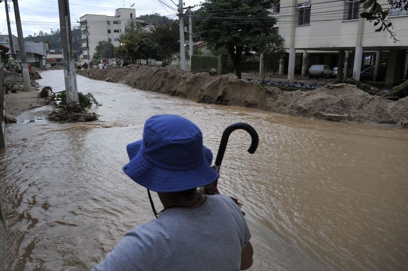 A woman attempts to cross a flooded street in central Nova Friburgo, Rio de Janeiro, Brazil.