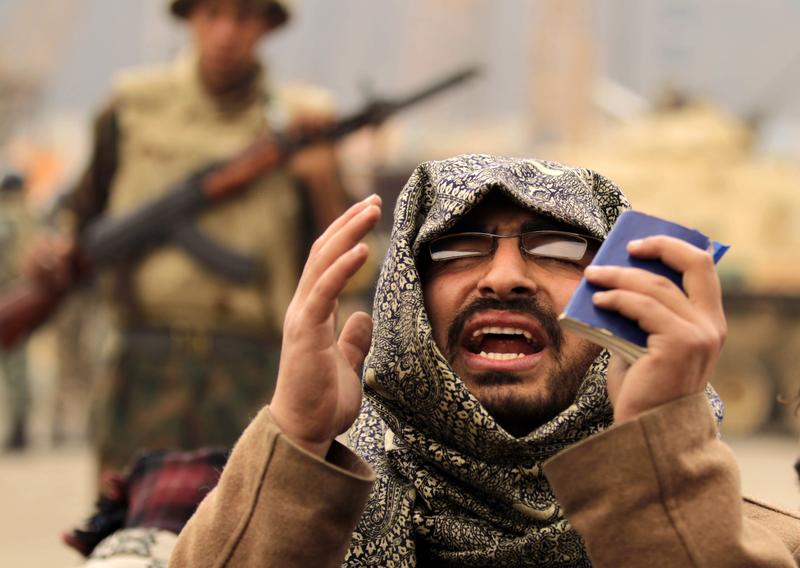 An Egyptian anti-government demonstrator and a member of the Egyptian Muslim Brotherhood movement prays in front of Egyptian soldiers at Cairo's Tahrir square on February 7, 2011.