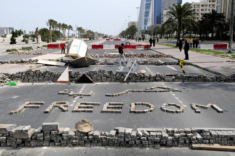 Bahraini anti-government protesters stand close to makeshift roadblocks in Manama on March 14, 2011, a day after Bahraini police clashed with demonstrators trying to occupy Manama's banking centre.