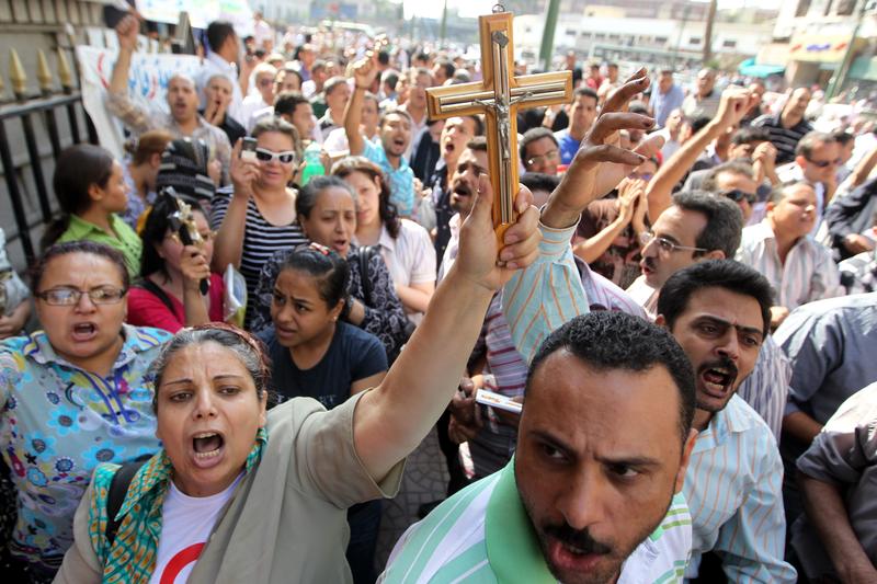 An Egyptian Coptic Christian raises a cross while others shout slogans during a demonstration outside the Cairo High Court on May 8, 2011.