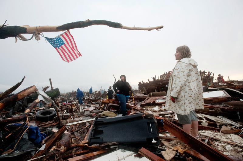 Sheila Bolte (L) and Ashley Hailey look up at the American flag they placed in a tree branch over the remains of Ashley's home after a tornado on May 23, 2011 in Joplin, Missouri.