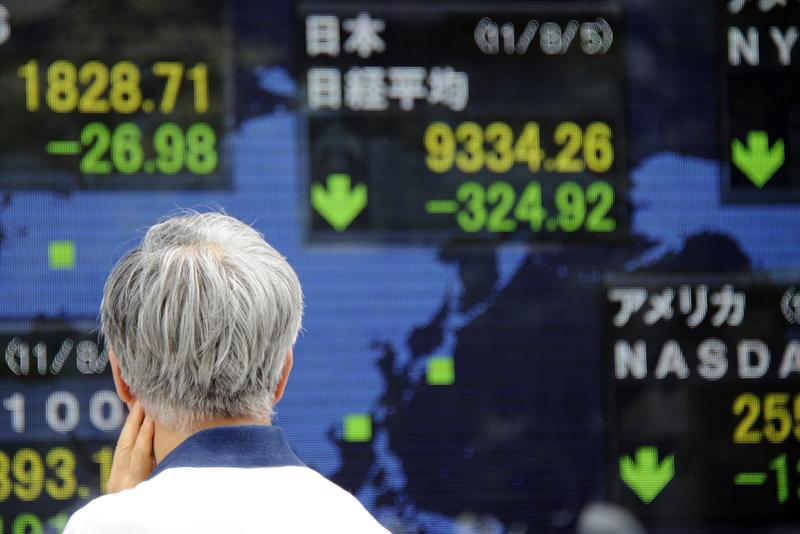 A businessman looks at an electric quotation board flashing the stock prices at a window of a security company in central Tokyo on August 5, 2011. Tokyo shares plunged 395.09 points or 4.09 percent.