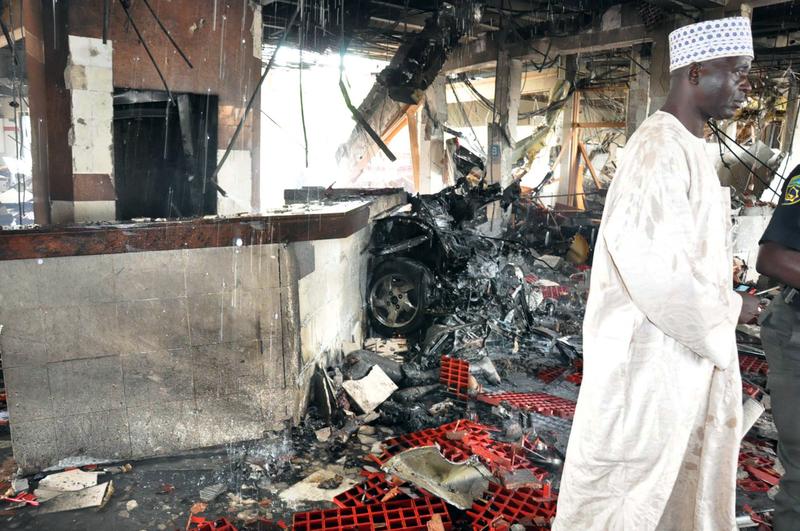 A man stands next to debris after a suicide bombing in Abuja, Nigeria.