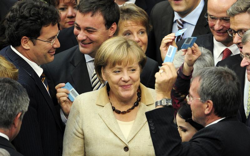 German Chancellor Angela Merkel (C) smiles surrounded by MPs holding their ballots on September 29, 2011 at the Lower House of German Parliament in Berlin.
