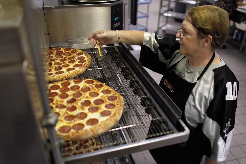 Alina Bernardini checks the temperature of pizzas as they come out of the oven during preparations for serving students lunch at Everglades High School on November 18, 2011 in Miramar, Florida.