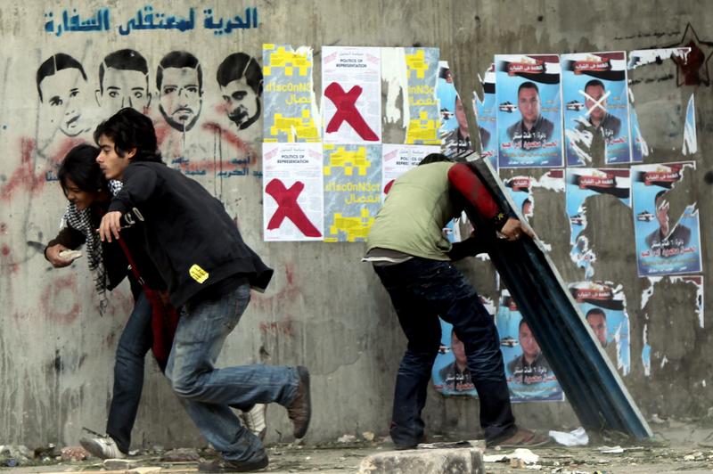 Egyptian protesters run for cover during clashes with riot police at Cairo's landmark Tahrir Square on November 20, 2011. Several hundred Egyptians occupied Cairo's Tahrir Square with sporadic clashes