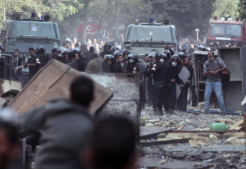Egyptian protesters take cover during clashes with riot police along a road which leads to the Interior Ministry, near Tahrir Square, in Cairo on November 23, 2011.