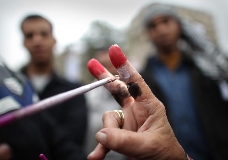 A woman makes a victory sign as her fingers are painted with the colours of the Egyptian flag in Tahrir Square.