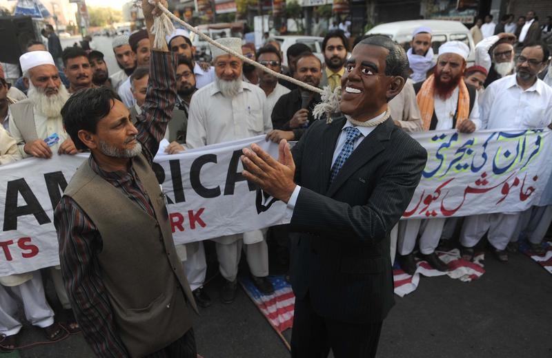 A Pakistan man pulls on a rope around the neck of a demonstrator wearing a mask of US President Barack Obama during an anti-US protest in Karachi on February 26, 2012.