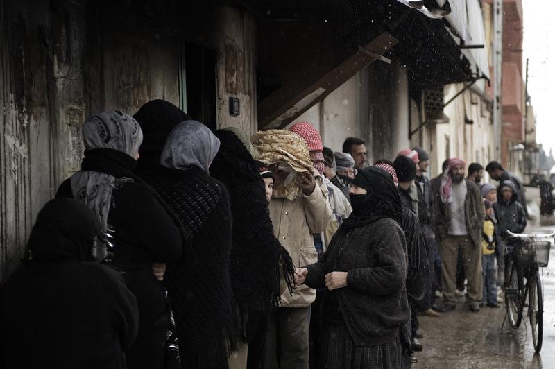 Syrians queue for bread outside a bakery in Qusayr, nine miles from Homs.