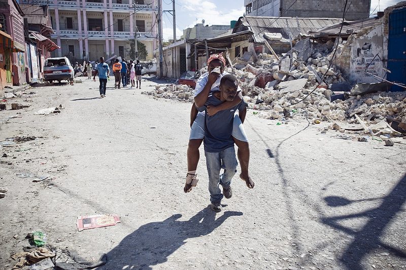 Man carries a woman to a makeshift clinic on his back on Saturday January 16, 2010 in Port-au-Prince, Haiti.