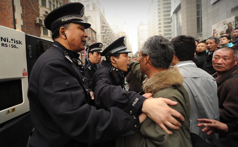 Policemen tell a group of people to move on who had gathererd in a street in Shanghai on February 27, 2011.
