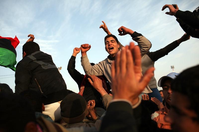 Men who have recently arrived from Libya celebrate at the border while waiting to be assigned to buses to take them to a transit camp on February 26, 2011 in Ras Jdir, Tunisia