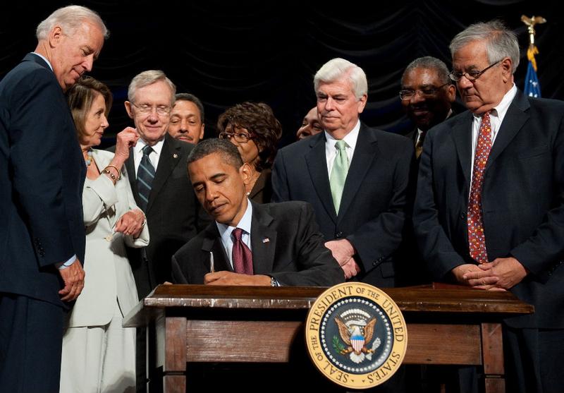 U.S. President Barack Obama signs the Dodd-Frank Wall Street Reform and Consumer Protection Act alongside members of Congress, the administration and U.S. Vice President Joe Biden