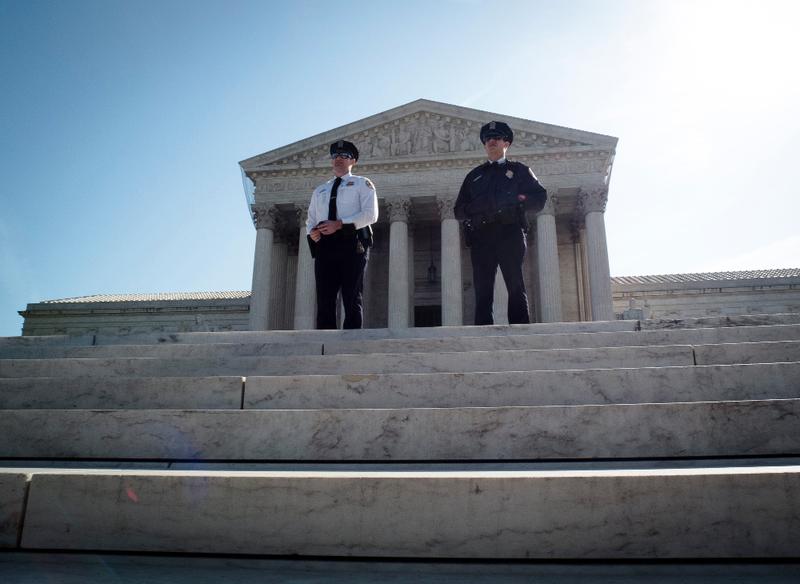 Two policemen guard outside the US Supreme Court on the third day of oral arguements over the constitutionality of the Patient Protection and Affordable Care Act on March 28, 2012 in Washington, DC.
