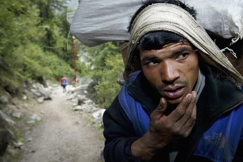 A Sherpa porter rests whist carrying a heavy load up the Everest trail May 25, 2003 in the Solu Khumbu region, Nepal.
