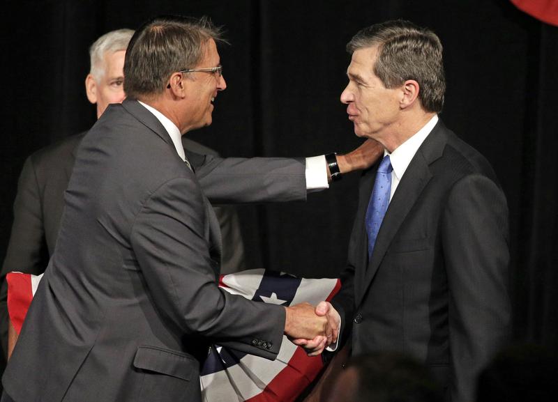 North Carolina Gov. Pat McCrory, left, shakes hands with North Carolina Attorney General Roy Cooper, right, after a candidate forum in Charlotte, N.C., Friday, June 24, 2016.