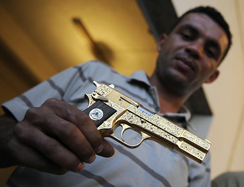 Libyan National Transitional Council (NTC) fighter Nabil Ali Dagouich holds Qaddafi's golden gun after participating in his capture a day before. Oct. 21, 2011