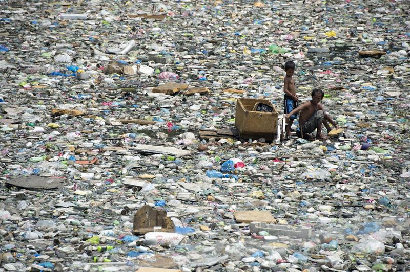 A father and son on a makeshift boat made from styrofoam paddle through a garbage filled river as they collect plastic bottles that they can sell in junkshops in Manila on March 19, 2015.
