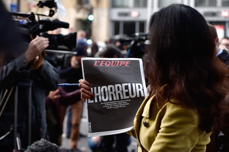 A Sky News journalist holds a French newspaper after a terrorist attack on November 14, 2015 in Paris, France.