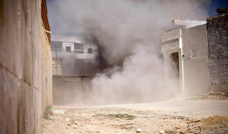 A street is choked with dust and debris from an exploding shell fired by government tanks that have advanced into Saraquib city on April 9, 2012 in Syria.