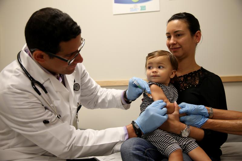 Daniela Chavarriaga holds her daughter, Emma Chavarriaga, as pediatrician Jose Rosa-Olivares, M.D. administers a measles vaccination during a visit to the Miami Children's Hospital.