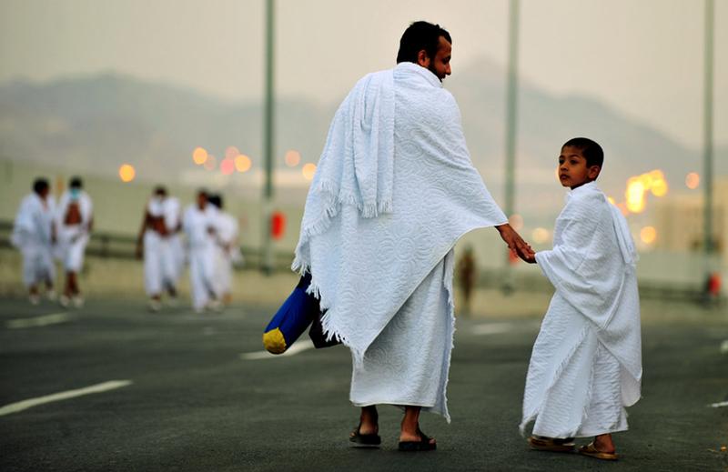 A Muslim pilgrim walks with his son along the road in the Mina valley three miles east of the Saudi Arabian holy city of Mecca during the Hajj, on November 14, 2010