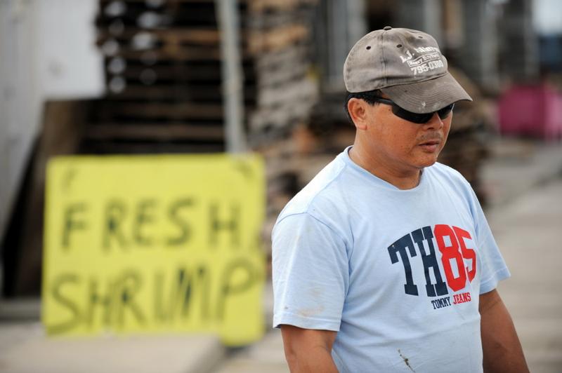 Boat owner Can Nguyen stand near a sign at a shrimp processor on a dock May 3, 2010 in Pass Christian, Miss., as he and the fleet are confined to port since the shutdown of all fishing on the Gulf.