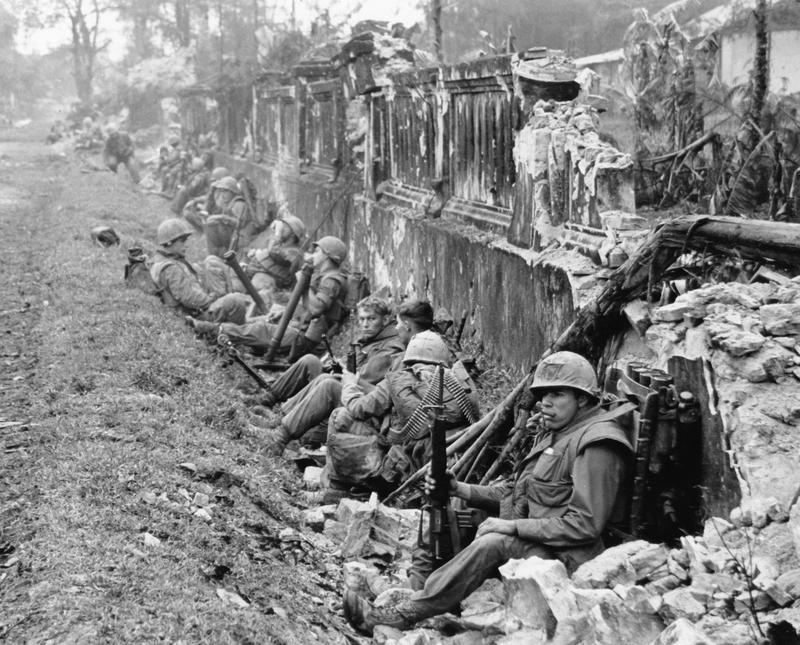 A unit of U.S. Marines rests alongside a battered wall of Hue's imperial palace after a battle for the Citadel in February 1968, during the Tet Offensive.