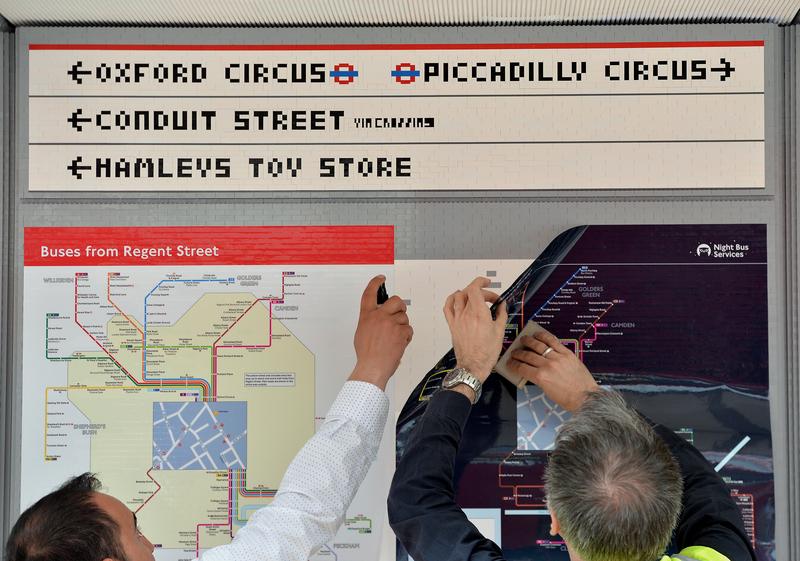 Putting the finishing touches on a London bus stop built entirely out of Lego.