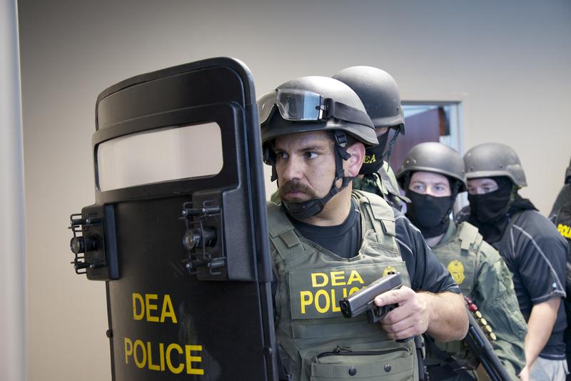 A group of Drug Enforcement Agency officers draw their weapons.
