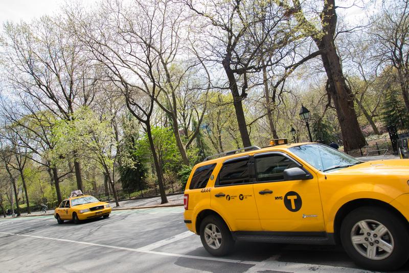 Taxis pass Washington Square Park on a sunny day in late April.