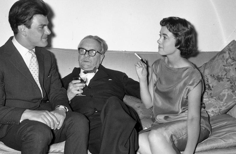 Raymond Chandler (1888 - 1959), centre, at a party in Portman Square, London. On either side of him are publisher Anthony Blond (1928 - 2008) and Blond's wife Charlotte.
