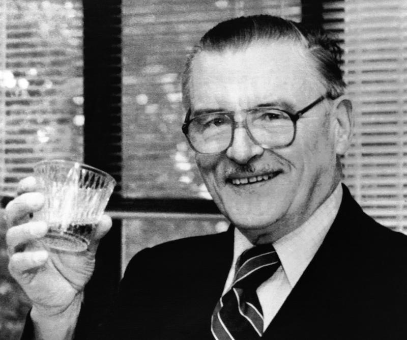 James McGill Buchanan, winner of the Nobel Memorial Prize in Economic Science, holds up a glass of champagne in his office in George Mason University, Virginia, USA on Oct. 16, 1986.