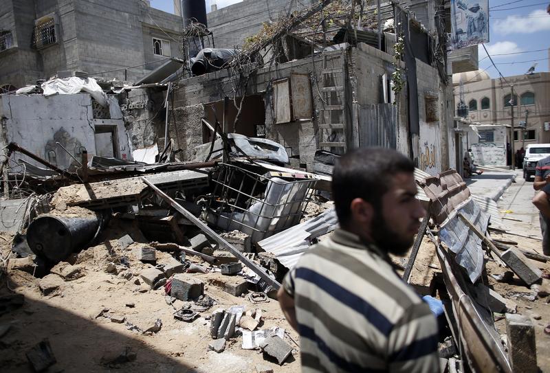 A Palestinian Hamas member stands guard in front of a destroyed building following an Israeli air strike on July 14, 2014 in Gaza City.