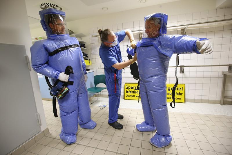 A nurse helps a doctor and nurse take off their isolation suits following a demonstration for the media of ebola treatment capabilities at Station 59 at Charite hospital on August 11, 2014 in Berlin.
