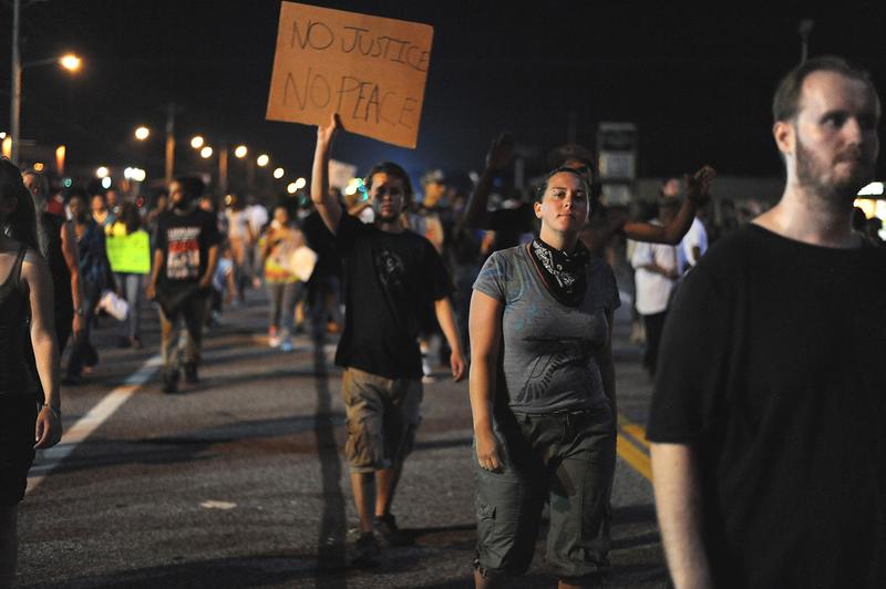 Demonstrators display signs during a protest on West Florissant Avenue in Ferguson, Missouri on August 18, 2014.